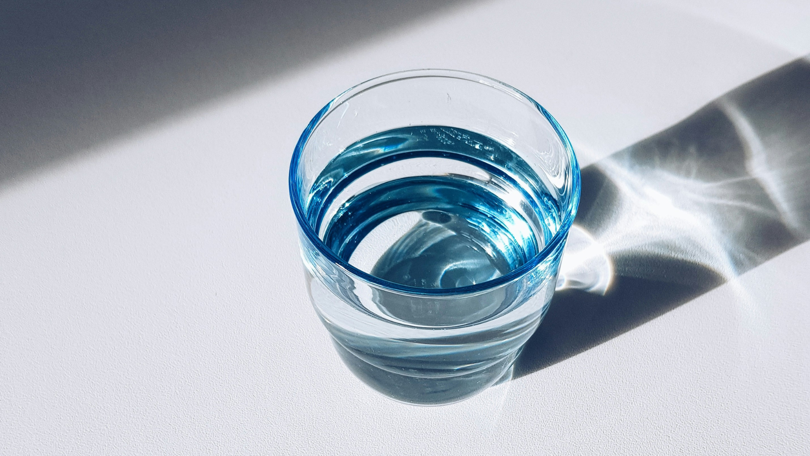 Bicchiere acqua con riflesso luce orizz